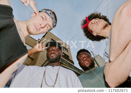 Low angle shot of biracial bad boy band dressed in street style clothes looking at camera Low angle shot of biracial bad boy band dressed in street style clothes looking at camera 117882671