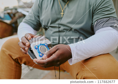 Unrecognizable male hands holding old fashioned tape recorder Unrecognizable male hands holding old fashioned tape recorder 117882677