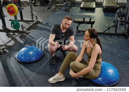 High angle shot of Caucasian male coach showing time result to his female athlete after training 117882698