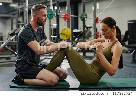 Personal trainer helping his athlete to swing press in empty gym 117882724