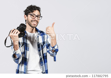 Smiling male photographer showing a camera and giving thumb up. Young man holding a camera and giving the thumb up, Smiling guy photographer showing a camera with thumb ok 117882795