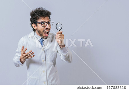 Surprised scientist observing with a magnifying glass to the side. Scientist holding a magnifying glass looking to the side, Man in a white coat with a magnifying glass looking advertisement 117882818