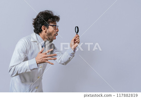 Scientist holding a magnifying glass looking to the side, Man in a white coat with a magnifying glass looking advertisement, Surprised scientist observing with a magnifying glass to the side Scientist holding a magnifying glass looking to the side, Man in a white coat with a magnifying glass looking advertisement, Surprised scientist observing with a magnifying glass to the side 117882819