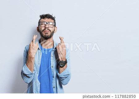 Worried person crossing his fingers making a wish, concerned man apologizing, hopeful man asking for help or apologizing, superstitious man crossing his fingers asking for something Worried person crossing his fingers making a wish, concerned man apologizing, hopeful man asking for help or apologizing, superstitious man crossing his fingers asking for something 117882850
