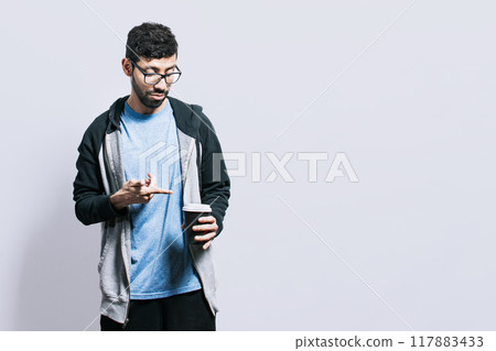 Person with coffee on isolated background, guy pointing disposable cup of coffee on isolated background, concept of a man showing looking at disposable cup of coffee Person with coffee on isolated background, guy pointing disposable cup of coffee on isolated background, concept of a man showing looking at disposable cup of coffee 117883433