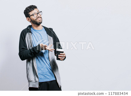 Smiling person with coffee on isolated background, guy pointing disposable cup of coffee on isolated background, concept of a man showing looking at disposable cup of coffee 117883434