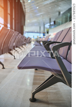 Empty chairs in airport departure hall, blurred airplane in the background. Empty chairs in airport departure hall, blurred airplane in the background. 117885023