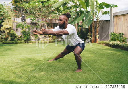 Strong man exercising on lawn in backyard of house Strong man exercising on lawn in backyard of house 117885438