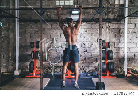 Unrecognizable black man athlete doing abs exercise on horizontal bar 117885444