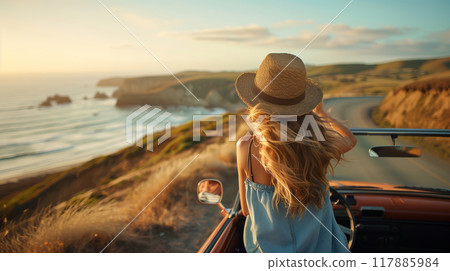 A woman in a straw hat is driving a car on a road near the ocean 117885984