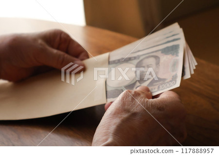 老婦人把錢裝在棕色信封裡 117888957