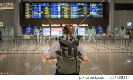 Young Asian woman in international airport looking at flight information board, checking her flight Young Asian woman in international airport looking at flight information board, checking her flight 117889214