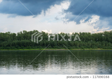 Serene landscape of forest and calm lake, with reflections of trees on the water. 117890168