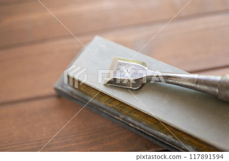 A well-used chisel and natural whetstone 117891594