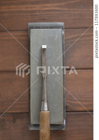 A well-used chisel and natural whetstone 117891600