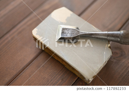 A well-used chisel and natural whetstone 117892233