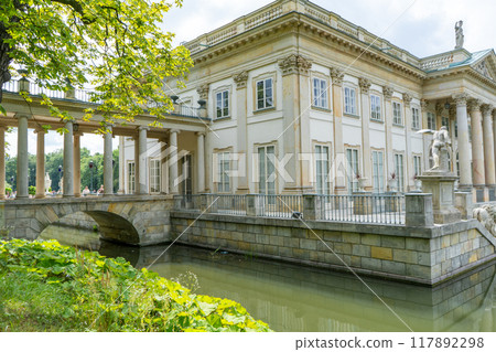Lazienki Park with pond. Polish Lazienkowski or Lazienki Krolewskie is the polish park. The palace on the water is a monument of architecture. 117892298