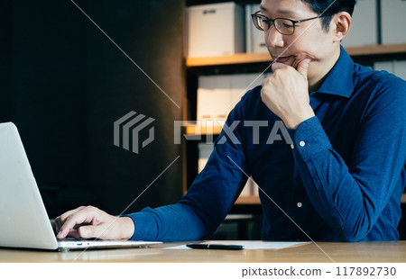 Middle-aged man facing a computer Middle-aged man facing a computer 117892730