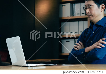 Middle-aged man facing a computer Middle-aged man facing a computer 117892741