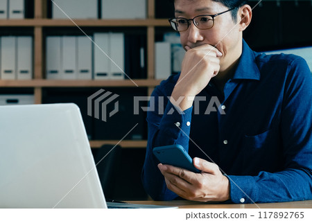 Middle-aged man facing a computer Middle-aged man facing a computer 117892765