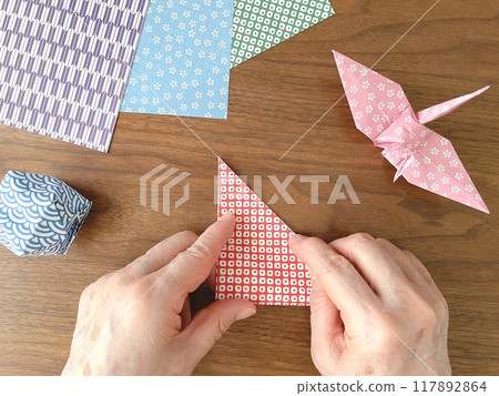 Hands of an elderly woman folding origami Hands of an elderly woman folding origami 117892864