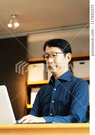 Middle-aged man facing a computer Middle-aged man facing a computer 117892975