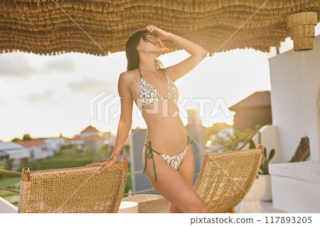 Stylish Woman in Bikini Enjoying Sunshine on Tropical Vacation Patio 117893205