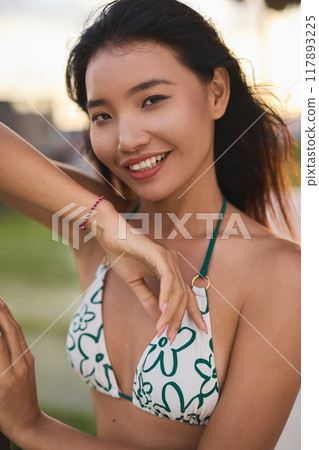 Smiling Woman in Floral Bikini Enjoying a Sunny Day at the Beach 117893225