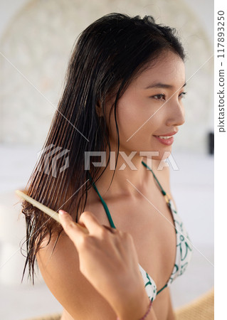 Hair Health. Woman Combing Wet Hair for Healthy Hair Care Routine in Relaxing Setting Hair Health. Woman Combing Wet Hair for Healthy Hair Care Routine in Relaxing Setting 117893250