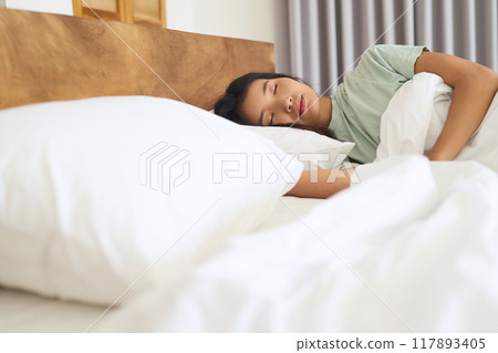Young Woman Sleeping Comfortably in Bed with Soft White Pillows 117893405