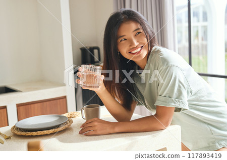 Healthy Morning. Woman Holding Glass of Water in Bright Modern Kitchen Setting 117893419