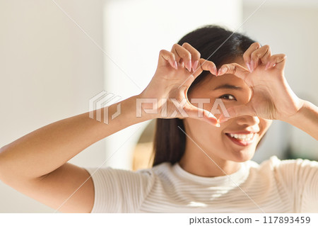 Eye Care. Woman Framing Eyes With Heart-Shaped Hands In Bright Light Eye Care. Woman Framing Eyes With Heart-Shaped Hands In Bright Light 117893459
