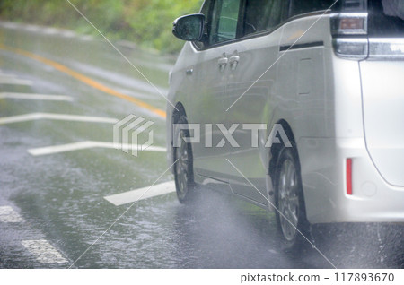 Water splashing from the rear wheels of a car driving on the road 117893670