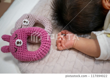Hand-knitted rattle and newborn baby's hand 117894022