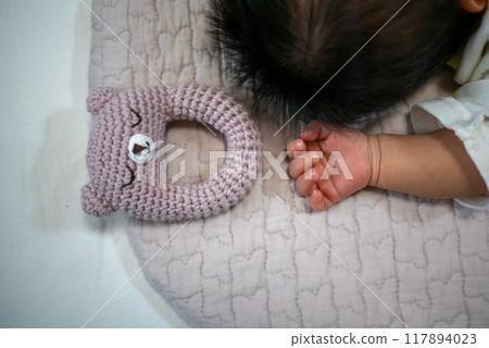 Hand-knitted rattle and newborn baby's hand 117894023