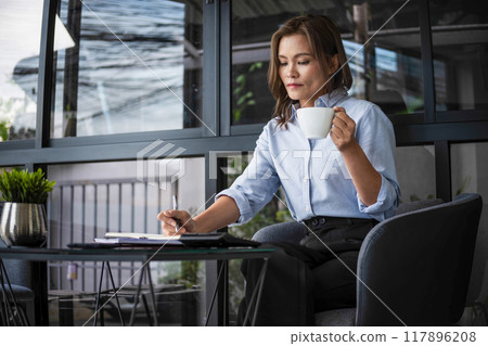 Businesswoman working while enjoying coffee. Businesswoman working while enjoying coffee. 117896208