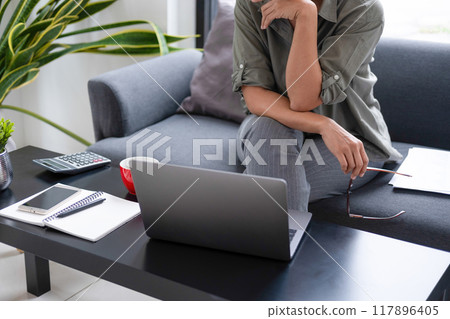 Businesswoman sitting at desk on couch in workplace or Businesswoman sitting at desk on couch in workplace or 117896405