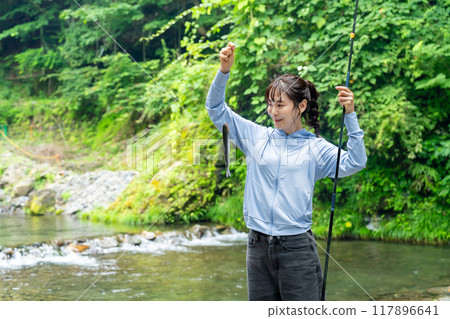 A woman fishing in a mountain stream A woman enjoying fishing 117896641