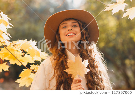 Smiling young woman portrait in the autumn forest with the yellow leaves at sunset 117897000
