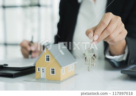 Real estate agent handing property keys to customer. 117897018