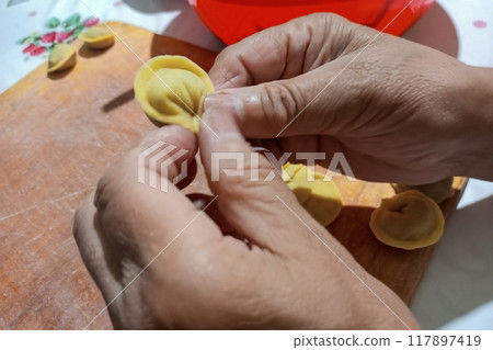 Process of modeling dumplings by hand, at end of which the ends of the dough wrapped in dough are pinched, inside which a piece of meat, potato, cheese filling is tightly squeezed. National cuisines 117897419