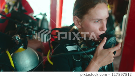 Woman prepares for scuba diving on a boat in thailand, checking her gear carefully before diving into the sea Woman prepares for scuba diving on a boat in thailand, checking her gear carefully before diving into the sea 117897812