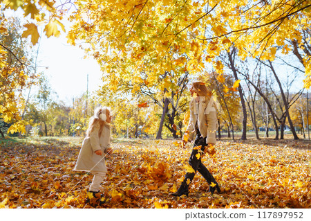Stylish mother and daughter enjoy the autumn park. Family on a walk. Childhood, walks, rest. Stylish mother and daughter enjoy the autumn park. Family on a walk. Childhood, walks, rest. 117897952