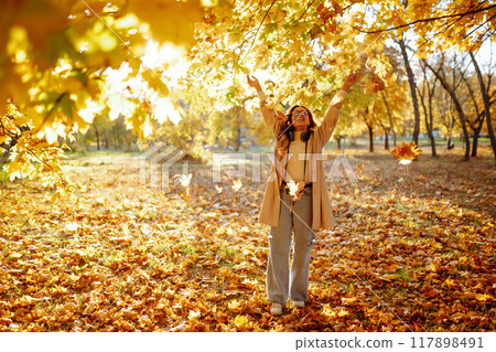 Beautiful woman taking pictures in autumn forest. Woman enjoying autumn weather. Lifestyle concept. 117898491