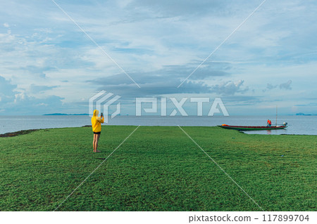 Woman in yellow hood walking on the wetland, Thale Noi, Thailand. Woman in yellow hood walking on the wetland, Thale Noi, Thailand. 117899704