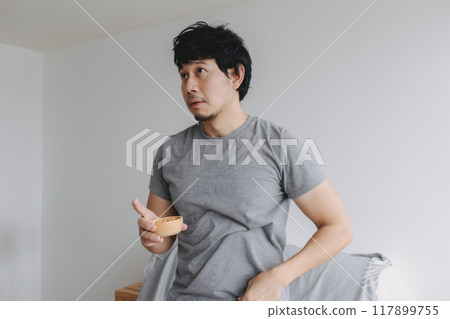Man eating snacks peanuts in the house to increase his protein and magnesium. Man eating snacks peanuts in the house to increase his protein and magnesium. 117899755