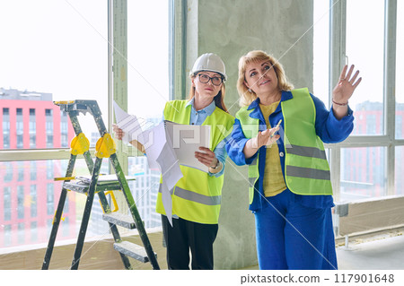 Two female industrial workers at construction site discussing work plans 117901648