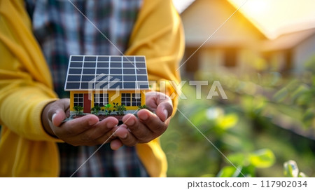 Architect holding model house with solar panels 117902034