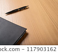 Notebooks and pens placed in a cluttered manner on a desk 117903162