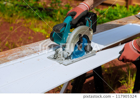 Before installing vinyl siding panels on facade of craftsman's home, he cuts them to desired size Before installing vinyl siding panels on facade of craftsman's home, he cuts them to desired size 117905324